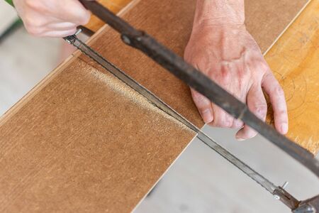 Installation laminate or parquet in the room, worker cuts a laminate of a certain length with a sawの写真素材
