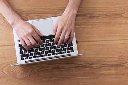 Man working on laptop, top view on male hands using laptopの写真素材