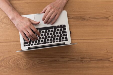 Man working on laptop, top view on male hands using laptopの写真素材