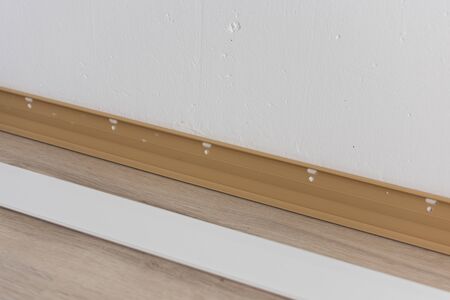 Installing plastic skirting board in the room, repair work in the houseの写真素材