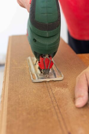 Installation laminate or parquet in the room, worker cuts a laminate of a certain length with a jigsawの写真素材