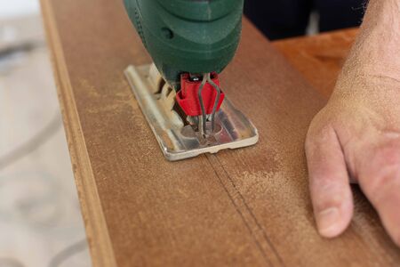 Installation laminate or parquet in the room, worker cuts a laminate of a certain length with a jigsawの写真素材