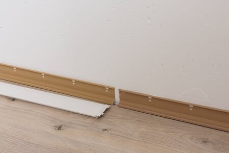 Installing plastic skirting board in the room, repair work in the houseの写真素材