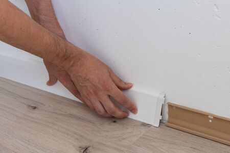 Worker installing plastic skirting board, repair work in the houseの写真素材