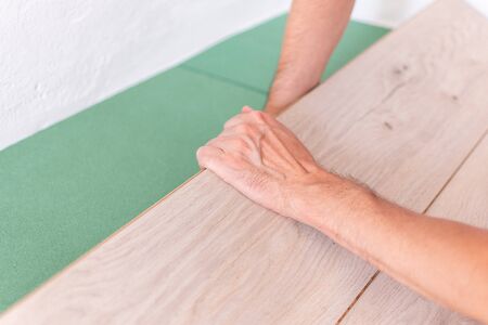 Installation laminate or parquet in the room, worker installing wooden laminate flooring, environmentally friendly soundproofing sheetsの写真素材