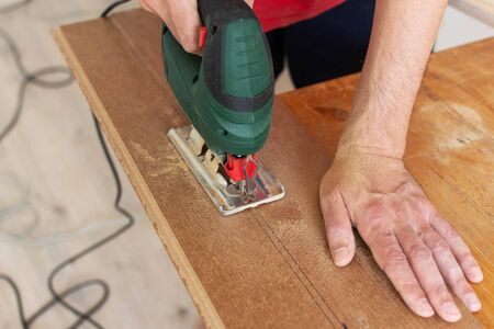 Installation laminate or parquet in the room, worker cuts a laminate of a certain length with a jigsawの写真素材