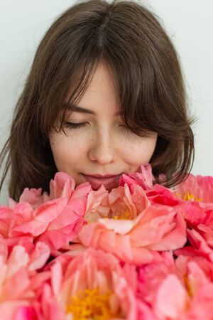 Beautiful happy girl smiling on her birthday, face of a girl close up with peonies, valentine's dayの写真素材