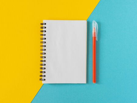 Open spiral notepad on colored background , notebook and pen lie on textural papers, flat lay conceptの写真素材