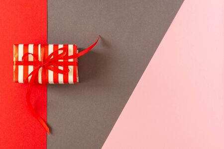Festive bright colorful background, gift with ribbon and bow on colored papersの写真素材