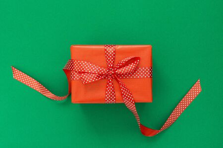 Festive background with gift, red gift box with ribbon in polka dots and bow on green background, flat lay, top viewの写真素材
