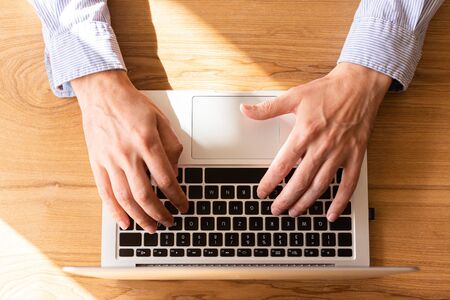Businessman working on laptop, top view on male hands using laptopの写真素材