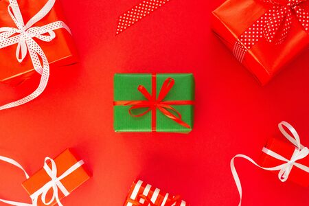 Festive background with colored gifts, gift boxes with ribbon and bow on red background, flat lay, top viewの写真素材