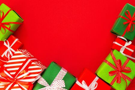 Festive background with colored gifts, gift boxes with ribbon and bow on red background, flat lay, top view, empty space for textの写真素材