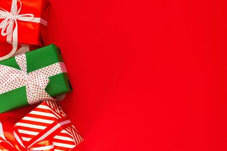 Festive background with colored gifts, gift boxes with ribbon and bow on red background, flat lay, top view, empty space for textの写真素材