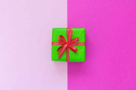 Festive background with gift, green gift box with ribbon in polka dots and bow on pink background, flat lay, top viewの写真素材