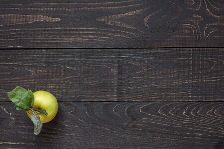Fresh organic yellow apple with leaves on a natural brown wooden backgroundの写真素材