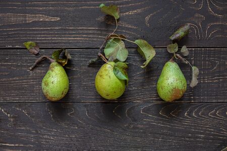 Fresh organic green pears with leaves in the center on a natural brown wooden backgroundの写真素材