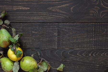 Fresh organic yellow apples and green pears with leaves on a natural brown wooden backgroundの写真素材