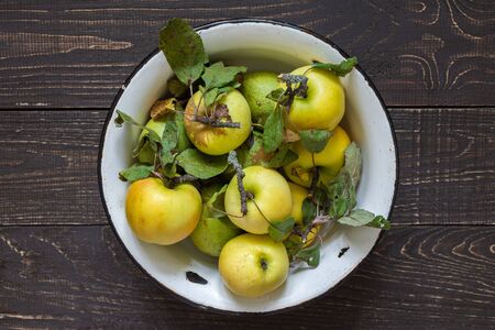 Fresh organic yellow apples and green pears in an iron bowl on a natural brown wooden backgroundの写真素材