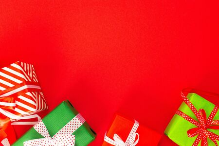 Festive background with colored gifts, gift boxes with ribbon and bow on red background, flat lay, top view, empty space for textの写真素材