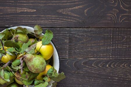 Fresh organic yellow apples and green pears in an iron bowl on a natural brown wooden backgroundの写真素材