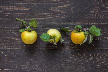 Fresh organic yellow apples with leaves in the center on a natural brown wooden backgroundの写真素材