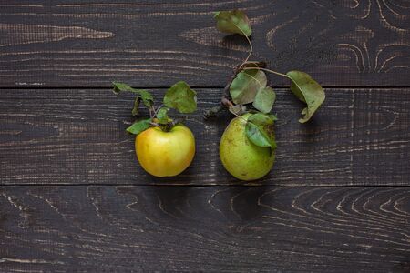 Fresh organic yellow apple and green pear in the center on a natural brown wooden backgroundの写真素材