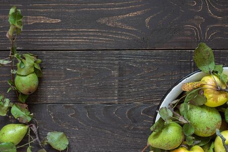 Fresh organic yellow apples and green pears in an iron bowl on a natural brown wooden backgroundの写真素材