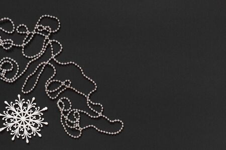 Holiday background , white snowflake and silver decorative beads on black background, flat lay, top viewの写真素材