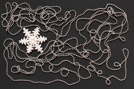 Holiday background , white snowflake and silver decorative beads on black background, flat lay, top viewの写真素材