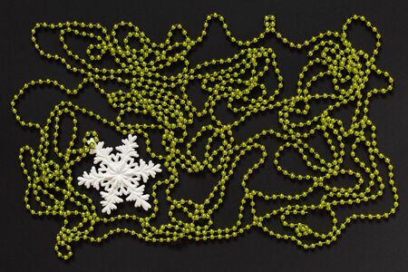 Holiday background , white snowflake and green bright decorative beads on black background, flat lay, top viewの写真素材