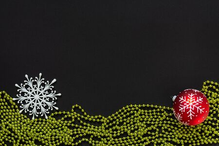 Holiday background , red christmas ball and snowflake and green bright decorative beads on black background, flat lay, top viewの写真素材