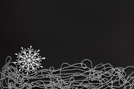 Holiday background , white snowflake and silver decorative beads on black background, flat lay, top viewの写真素材