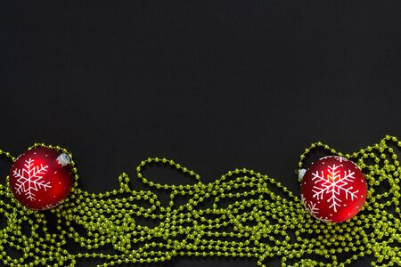 Holiday background , red christmas balls with snowflake and green bright decorative beads on black background, flat lay, top viewの写真素材