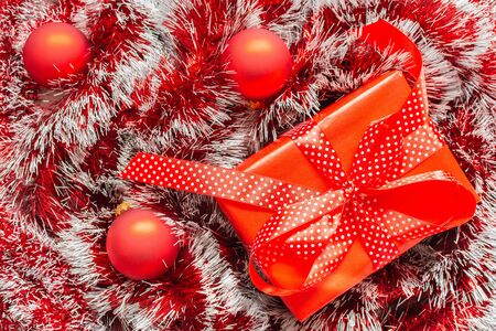 Holiday background ,red bright shiny Christmas garland ,gift box with ribbon in polka dots and bow and Christmas ballsの写真素材