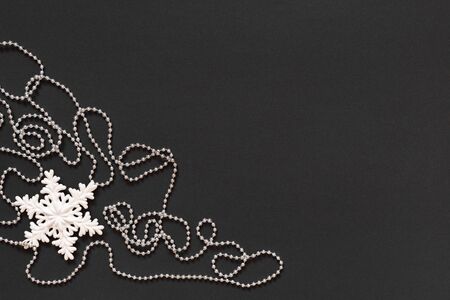 Holiday background , white snowflake and silver decorative beads on black background, flat lay, top viewの写真素材