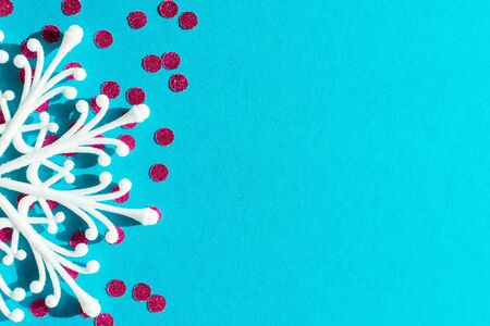 White snowflake and bright pink round confetti on a blue background, holiday backgroundの写真素材