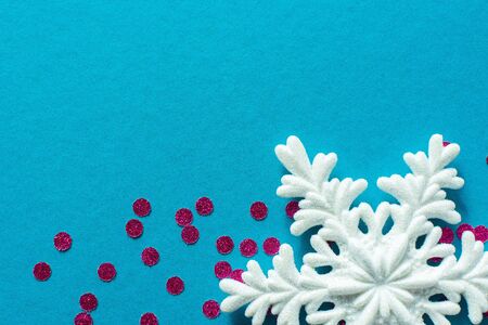 White snowflake and bright pink round confetti on a blue background, holiday backgroundの写真素材