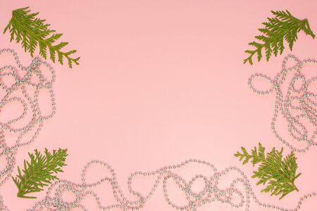 Holiday christmas background, fir branches and silver decorative beads on pink background, flat lay, top viewの写真素材