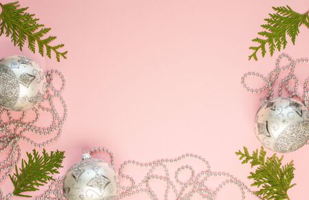Holiday christmas background, fir branches and silver decorative beads, christmas balls on pink background, flat lay, top viewの写真素材