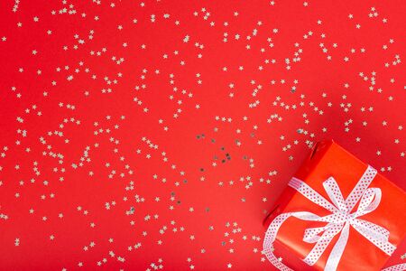 Festive background , gift box with ribbon and bow on a red background with glitter silver stars, flat lay, top viewの写真素材