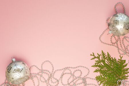 Holiday christmas background, fir branches and silver decorative beads, christmas balls on pink background, flat lay, top viewの写真素材
