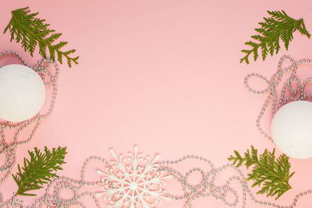 Holiday christmas background, fir branches and silver decorative beads, white snowflakes and christmas balls on pink background, flat lay, top viewの写真素材