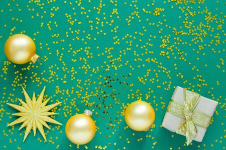 Holiday background , gold christmas balls and gift boxes on a green background with glitter gold stars, flat lay, top viewの写真素材