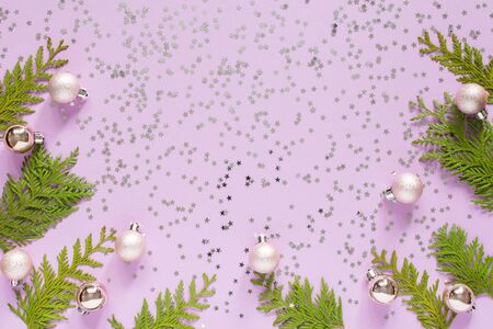 Holiday background , christmas balls and thuja twigs on a lilac background with glitter silver stars, flat lay, top viewの写真素材