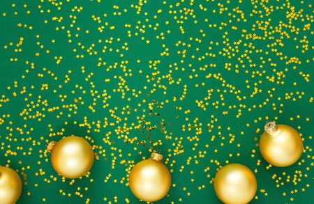 Holiday background , gold christmas balls on a green background with glitter gold stars, flat lay, top viewの写真素材