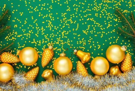 Holiday background , gold christmas balls and fir twigs and bright shiny christmas garland on a green background with glitter gold stars, flat lay, top viewの写真素材