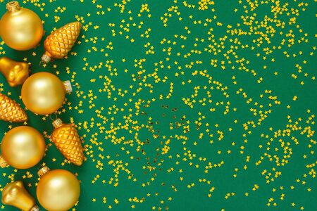 Holiday background , gold christmas balls on a green background with glitter gold stars, flat lay, top viewの写真素材