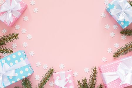 Holiday background , pink and blue gift boxes in polka dots with white ribbon and bow and spruce branches on a pink background with snowflakes , flat lay, top viewの写真素材