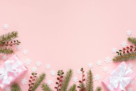 Holiday background , pink gift boxes in polka dots with white ribbon and bow and spruce branches on a pink background with snowflakes , flat lay, top viewの写真素材